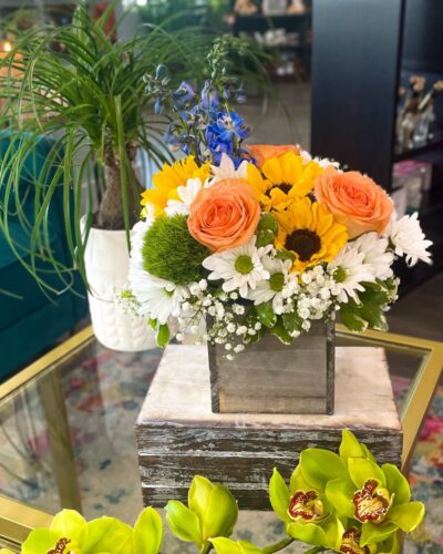 "Sunset on the Beach" flower arrangement with sunflowers, daisies, peach roses in a rustic wooden cube vase.